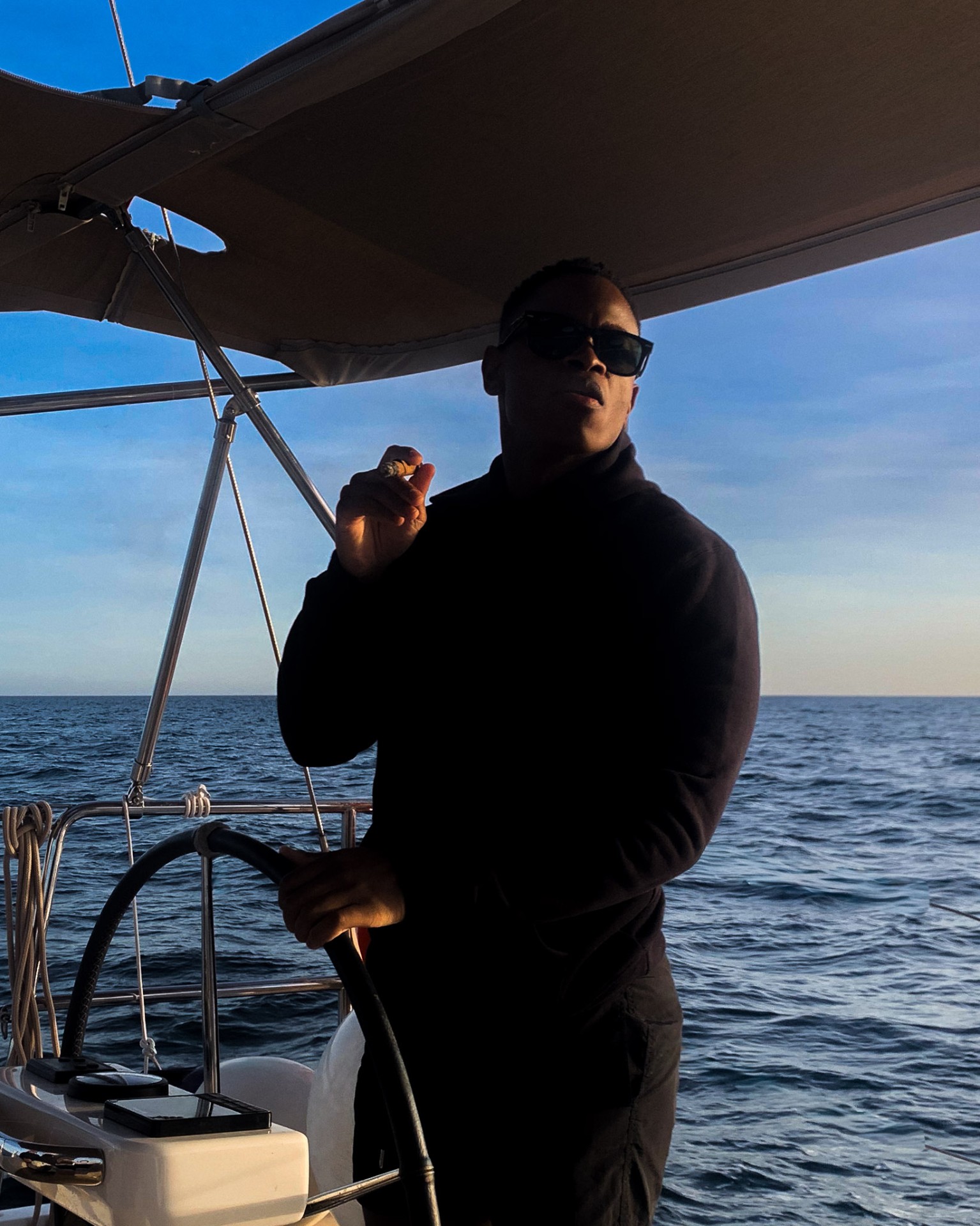 Man at yacht helm at dusk